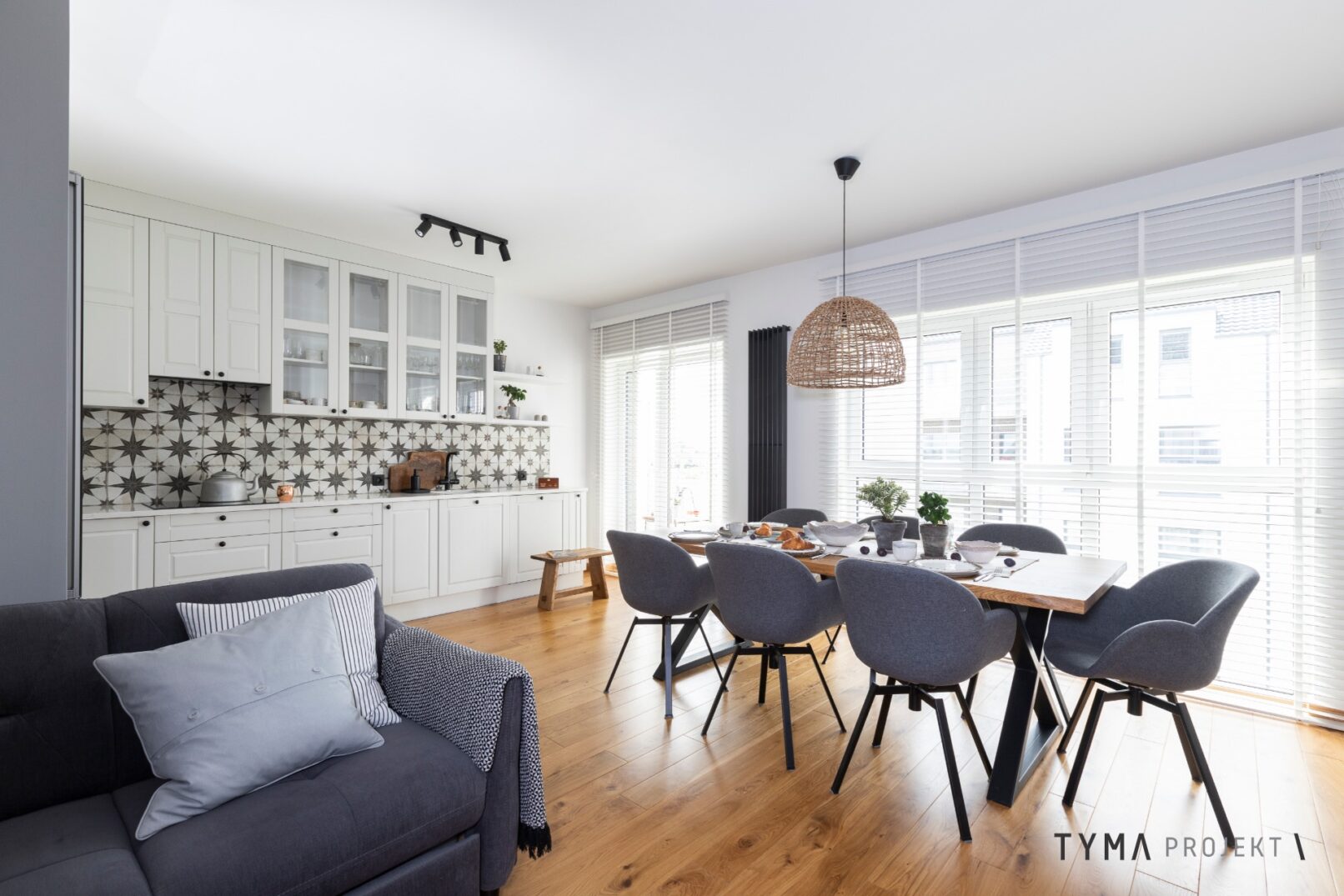 Biała kuchnia i jadalnia z masywnym stołem.