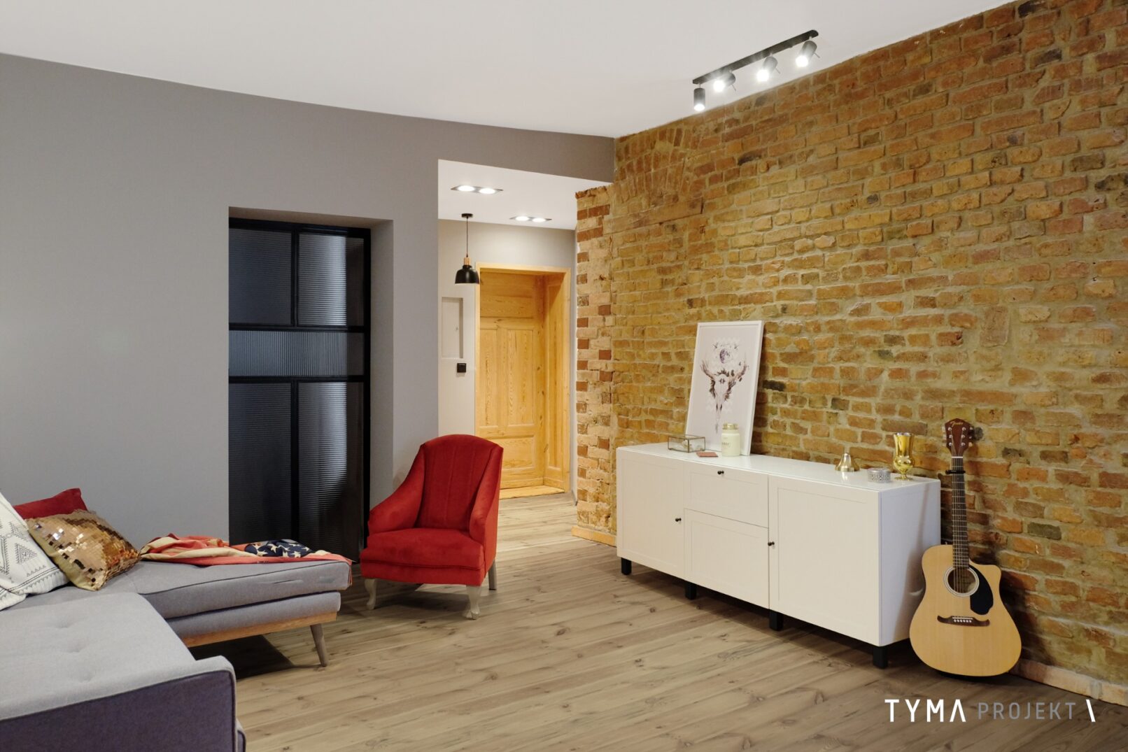 Salon z ceglaną ścianą i dodatkami boho.