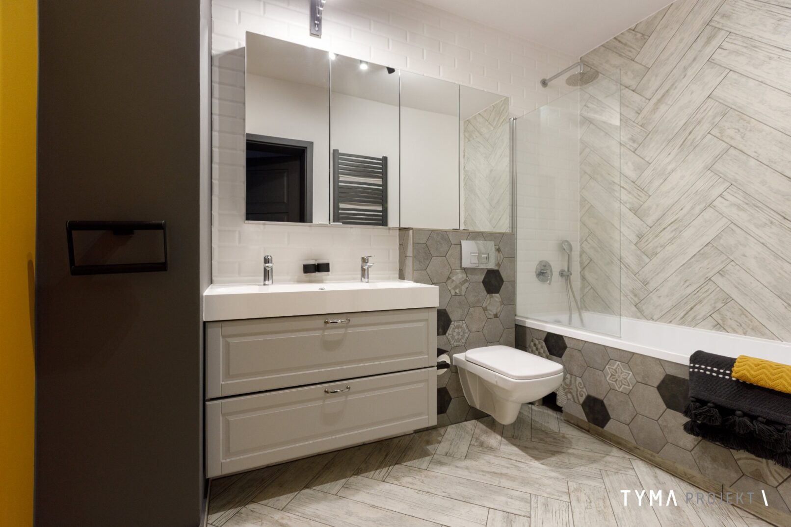 Łazienka w odcieniach bieli i szarości. Wanna z funkcją prysznica.