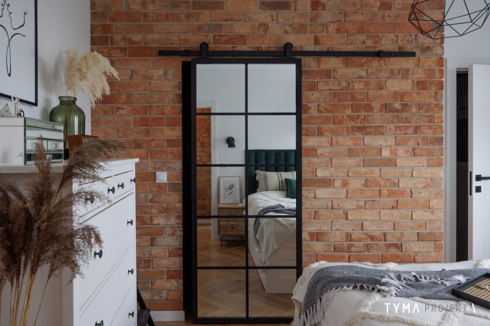Ceglana ściana skrywa przestronną garderobę.